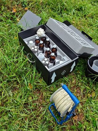 Otwarty pojemnik transportowy z próbkami wody; zdjęcie w terenie