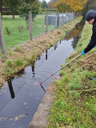 Pobór próbki wody z rowu melioracyjnego za pomocą czerpaka