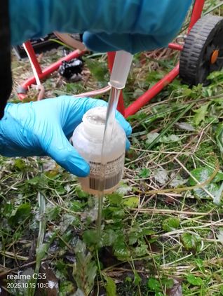 Pobór próbki wody do pojemnika laboratoryjnego; zdjęcie w terenie